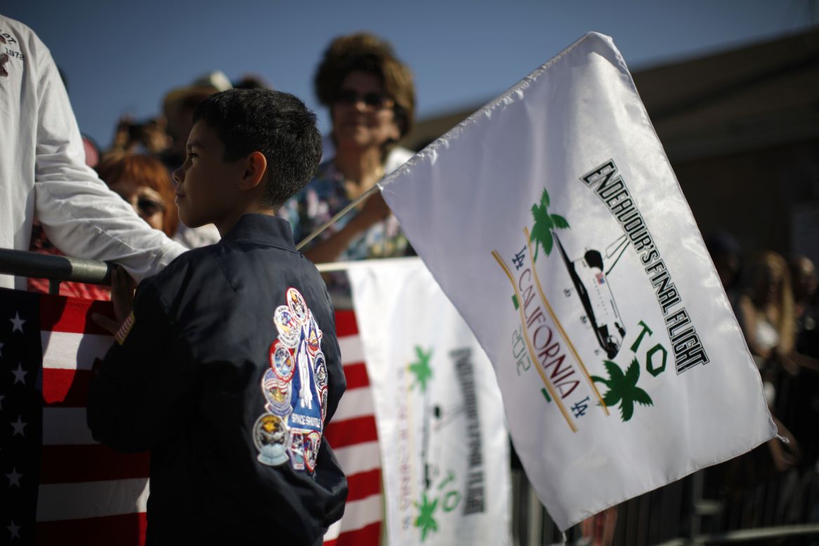 Kevin Alcaraz, 8, waves a flag from the crowd gathered along the shuttle's route.