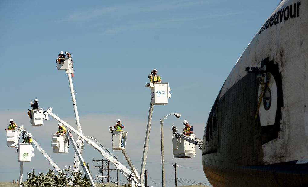 People take photos from cherry pickers Saturday as the shuttle moves along Crenshaw Drive in Inglewood, California.