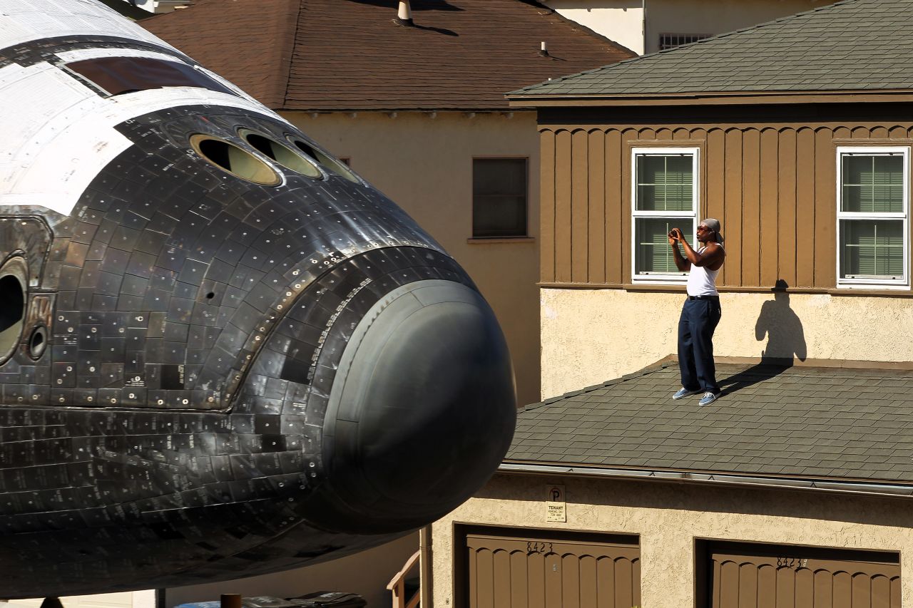 A man takes a picture from a rooftop as Endeavour makes its way toward the California Science Center on Saturday.