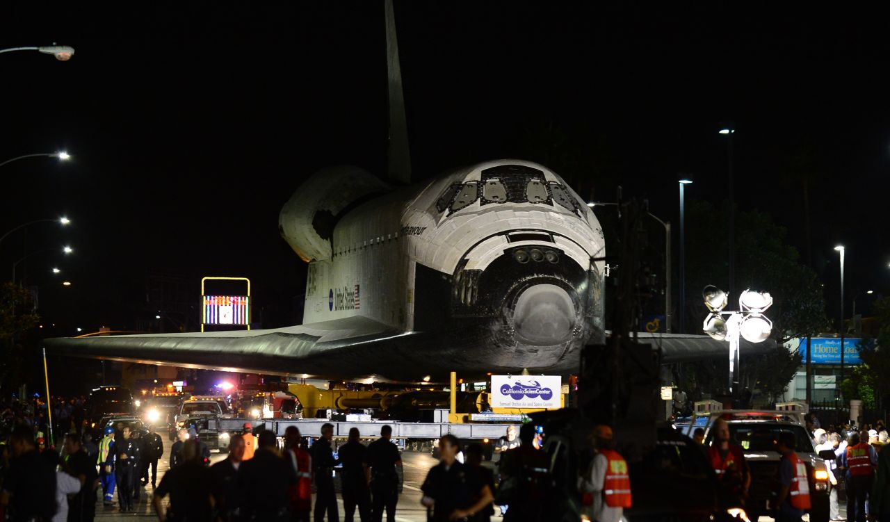 The space shuttle Endeavour makes its way down a city street under heavy escort on Saturday, October 13.