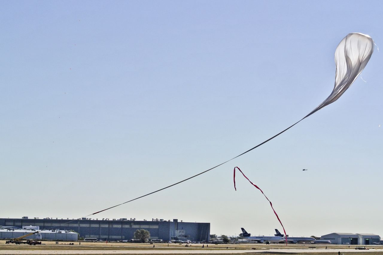 A crane carrying the capsule follows the helium balloon during the launch on Sunday.