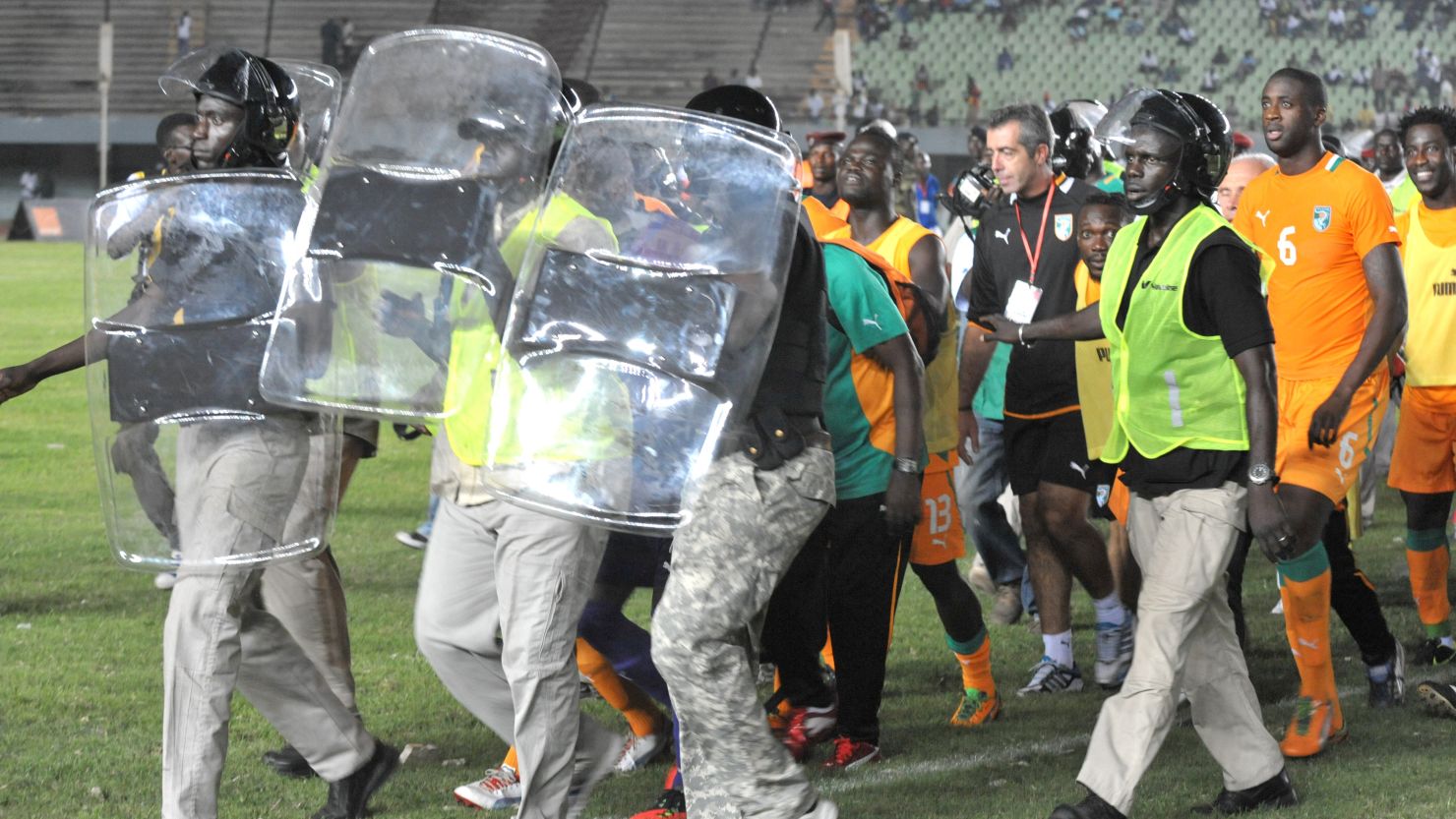 Ivory Coast's players are taken off the field under protection from riot police after the match against Senegal was abandoned.