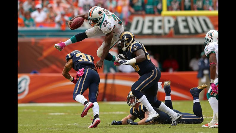 Reggie Bush of the Miami Dolphins jumps over No. 31 Cortland Finnegan of the St. Louis Rams on Sunday at Sun Life Stadium in Miami Gardens, Florida.
