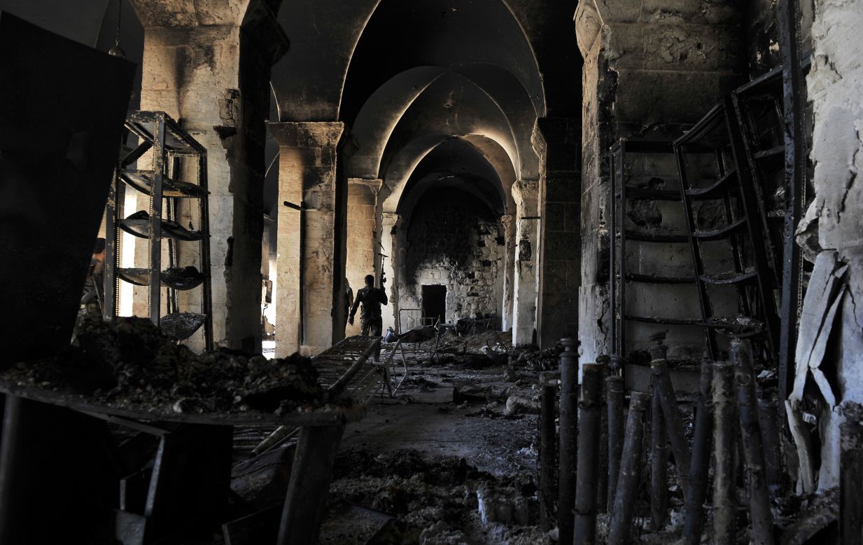 A Syrian rebel walks inside a burnt section of the Umayyad Mosque. Opposition activists reported that the 12th-century mosque was set afire during heavy fighting on Saturday, October 13.