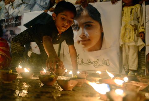 A Pakistani youth places an oil lamp next to a photograph of teen activist Malala Yousufzai on Friday, October 12, 2012, in Karachi, Pakistan. 