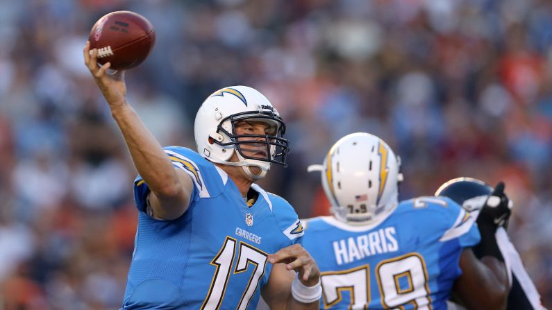Chargers quarterback Philip Rivers passes the ball as teammate Michael Harris blocks a Broncos defender.