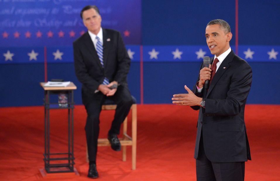 President Obama promotes his policies as Mitt Romney listens.