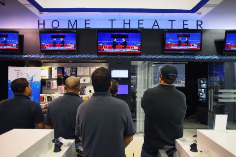 A group of men watch the presidential debate on television screens at an electronics store in Miami on Tuesday, October 16.
