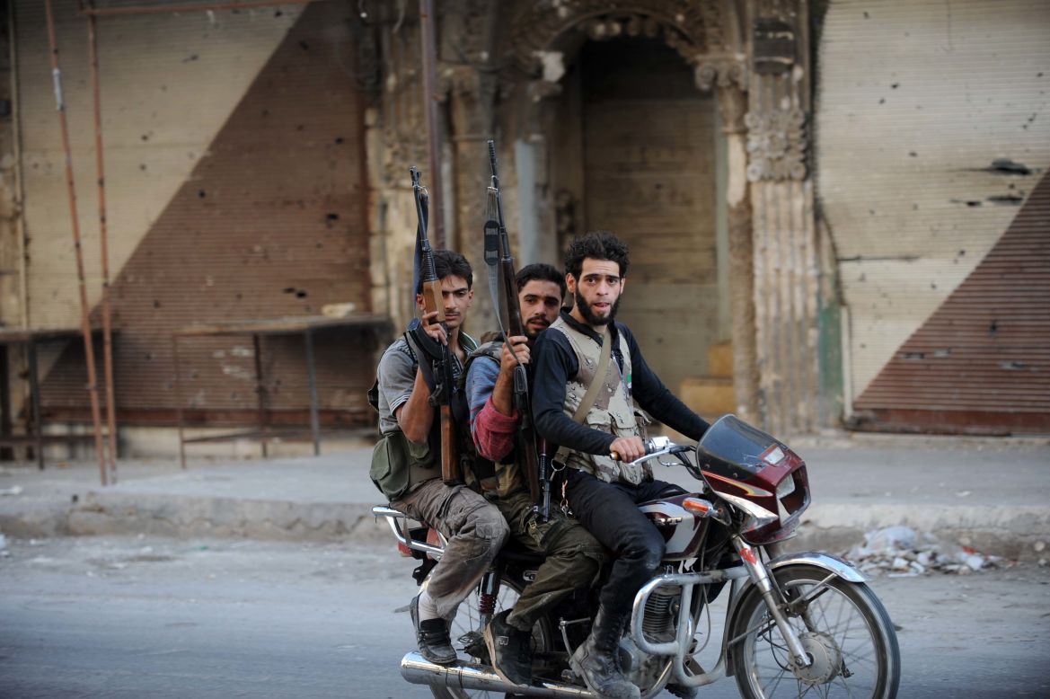 Syrian rebel fighters on Wednesday ride a motorcycle in Maaret al-Numan, an area under the control of rebel fighters in the northwestern Idlib province.