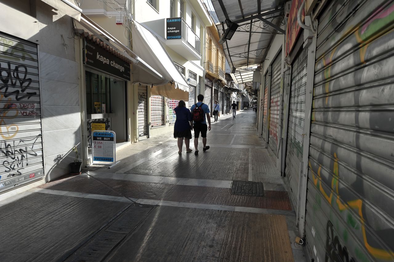 People walk by closed shops in Athens during the 24-hour strike. Greece's fourth national strike this year brought the country to a virtual standstill and shut down most of the transport system.
