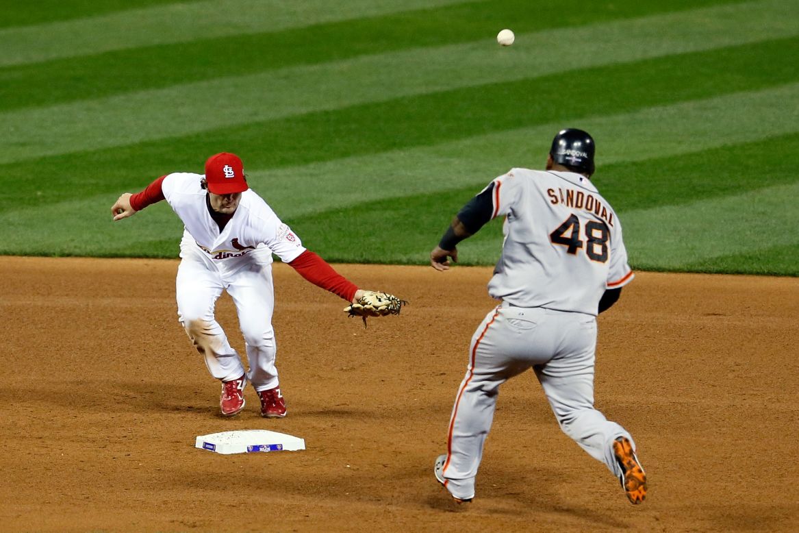 No. 38 Pete Kozma of the Cardinals is unable to field a throw by No. 31 pitcher Lance Lynn as No. 48 Pablo Sandoval of the Giants rounds second base in the fourth inning.