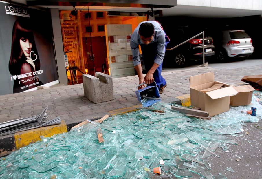 A worker on Saturday sweeps shattered glass outside damaged shops.