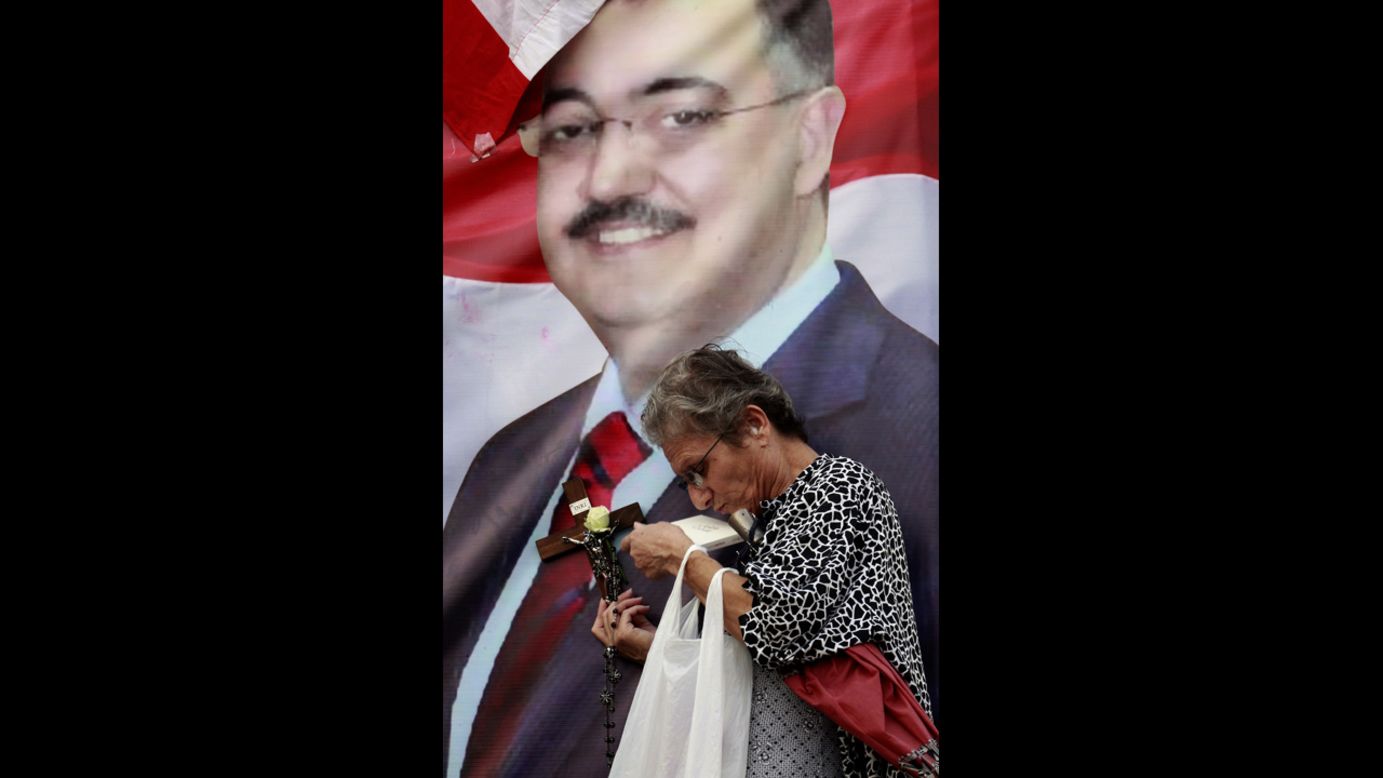A woman with a cross and a rosary prays at a poster with an image of al-Hassan, during a protest Saturday, October 20, against his killing.