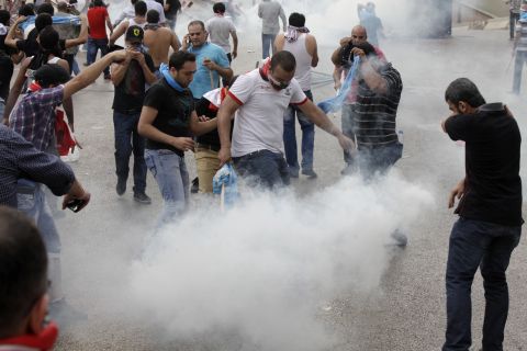 Protesters react to tear gas being fired at them by Lebanese police officers on Sunday.