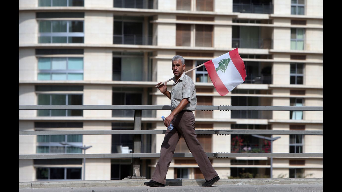 A Lebanese man holding the national flag watches the funeral procession on Sunday.