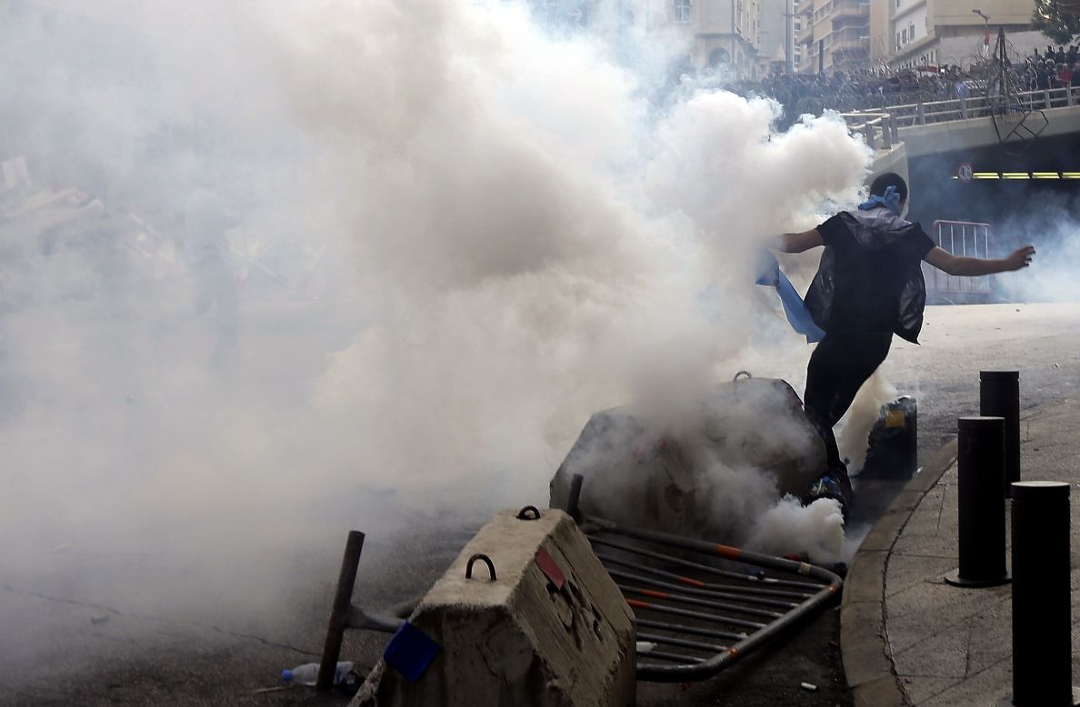 A demonstrator runs for cover from tear gas fired by Lebanese police on Sunday.
