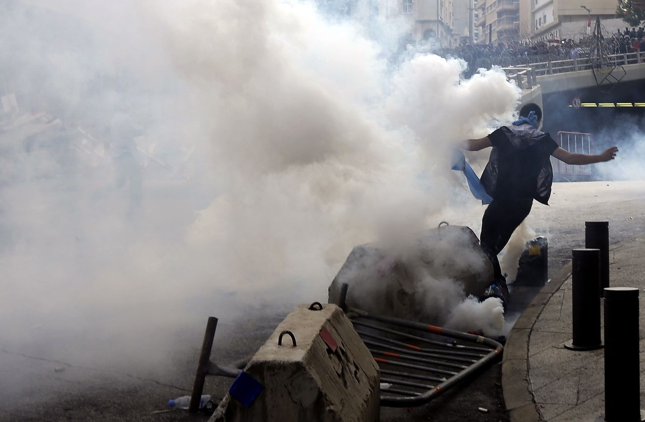 A demonstrator runs for cover from tear gas fired by Lebanese police on Sunday.