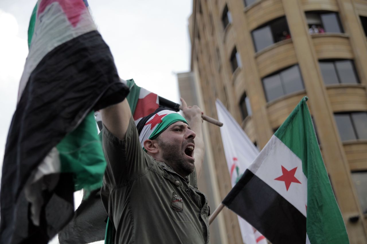 An anti-government protester waves a pre-Baath Syrian flag at a demonstration outside the govermental palace in Beirut, Lebanon, after a funeral for al-Hassan and his bodyguard on Sunday. The two men and one other person were killed in a car bombing on Friday.