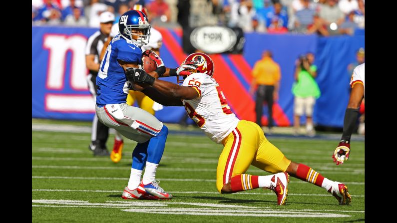 Victor Cruz of the Giants runs with the ball after a catch against London Fletcher of the Redskins on Sunday.