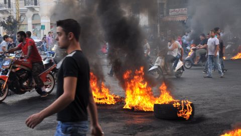 Protesters gather on motorbikes at a road block of burning tires in the northern Lebanese city of Tripoli, on October 20, 2012.