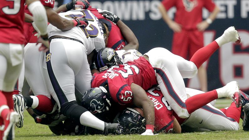 No. 72 Kelechi Osemele of the Baltimore Ravens has his leg pinned underneath him as No. 53 Bradie James of the Houston Texans falls on him Sunday at Reliant Stadium in Houston.