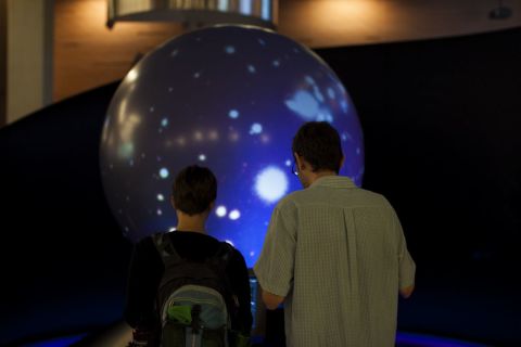 Two sci-fi enthusiasts interact with an exhibit called the "Magic Planet"at the Center for Science and the Imagination.