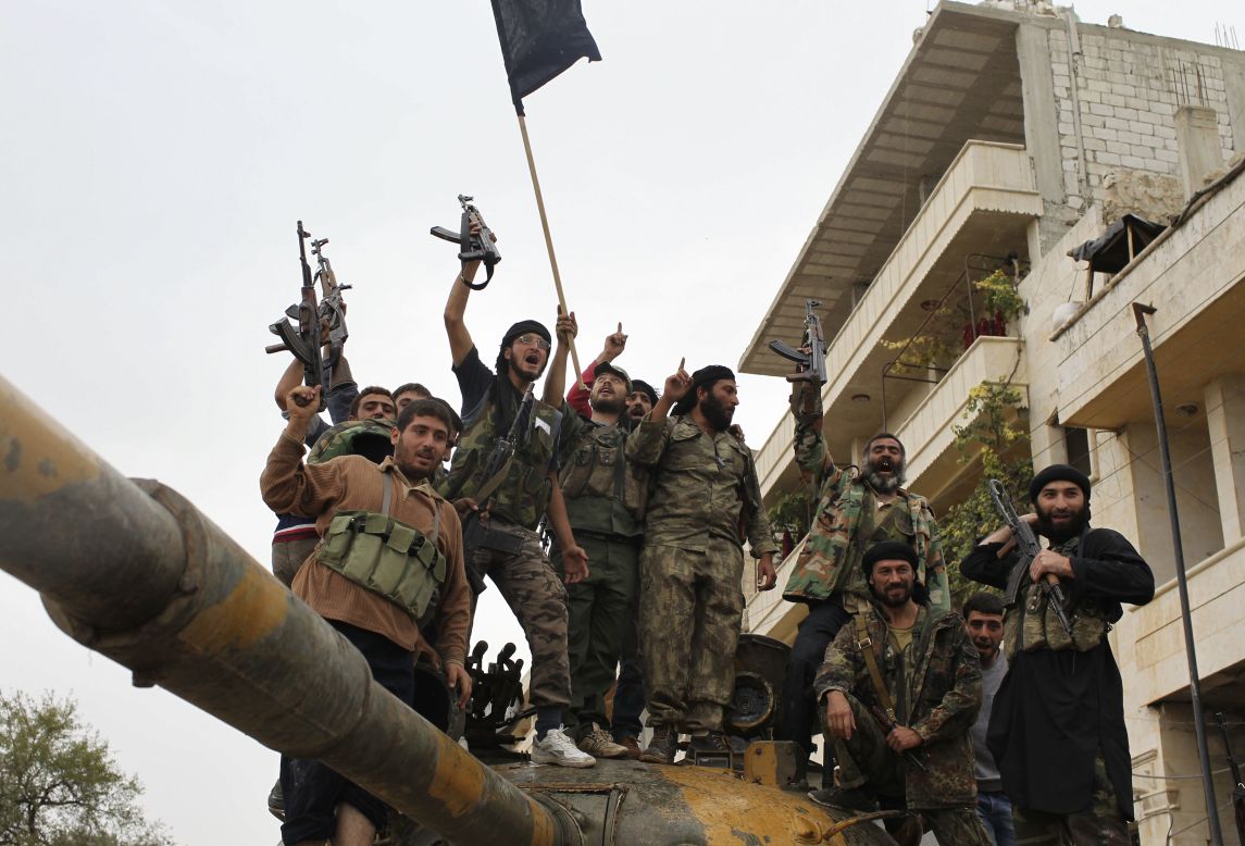 Members of the Free Syrian Army celebrate on a tank that belonged to pro-government forces after they took over the site from them early Monday in Salqin.