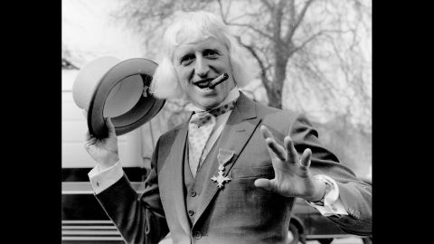 British radio disc jockey, television star and charity fund-raiser Sir Jimmy Savile poses for a photo at Buckingham Palace, London, after receiving the Order of the British Empire in 1972. Since his death a year ago at age 84, Savile has been knocked off his perch as a national treasure, accused of being a predatory pedophile who used his fame and position to abuse youngsters, sometimes on BBC premises.