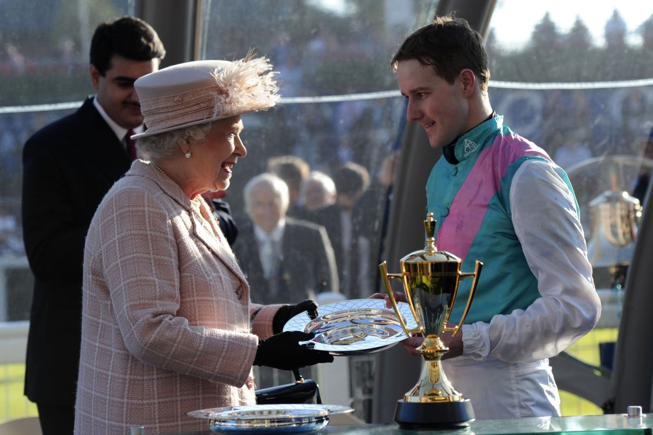 Queen Elizabeth II presents Frankel's jockey Tom Queally with the Champion Stakes trophy at Ascot.