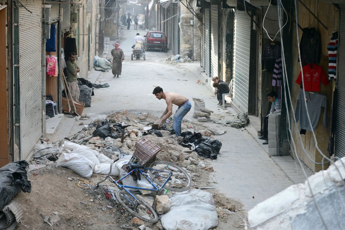 A shopkeeper clears the rubble from in front of his store in the old sector of Aleppo.