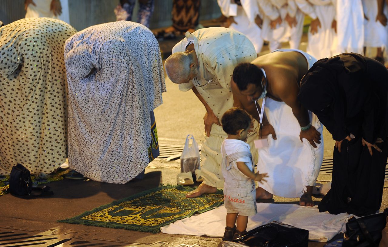 A child looks on as Muslim pilgrims perform evening prayers along a street close to the Grand Mosque in the holy city of Mecca on Tuesday.