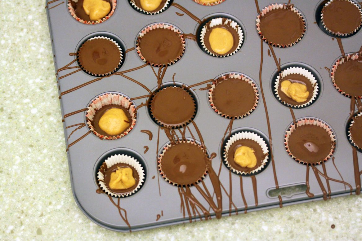 Cover each peanut butter disc with another layer of chocolate until the liner is filled completely. Gently tap the pan to remove any air bubbles.