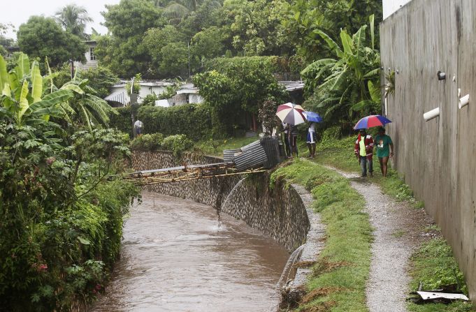 Jamaicans shelter themselves from the rain of approaching Hurricane Sandy as they walk along the Hope River on Wednesday.