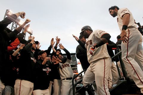 Sandoval celebrates with teammates in the dugout after scoring on a solo home run to center field.