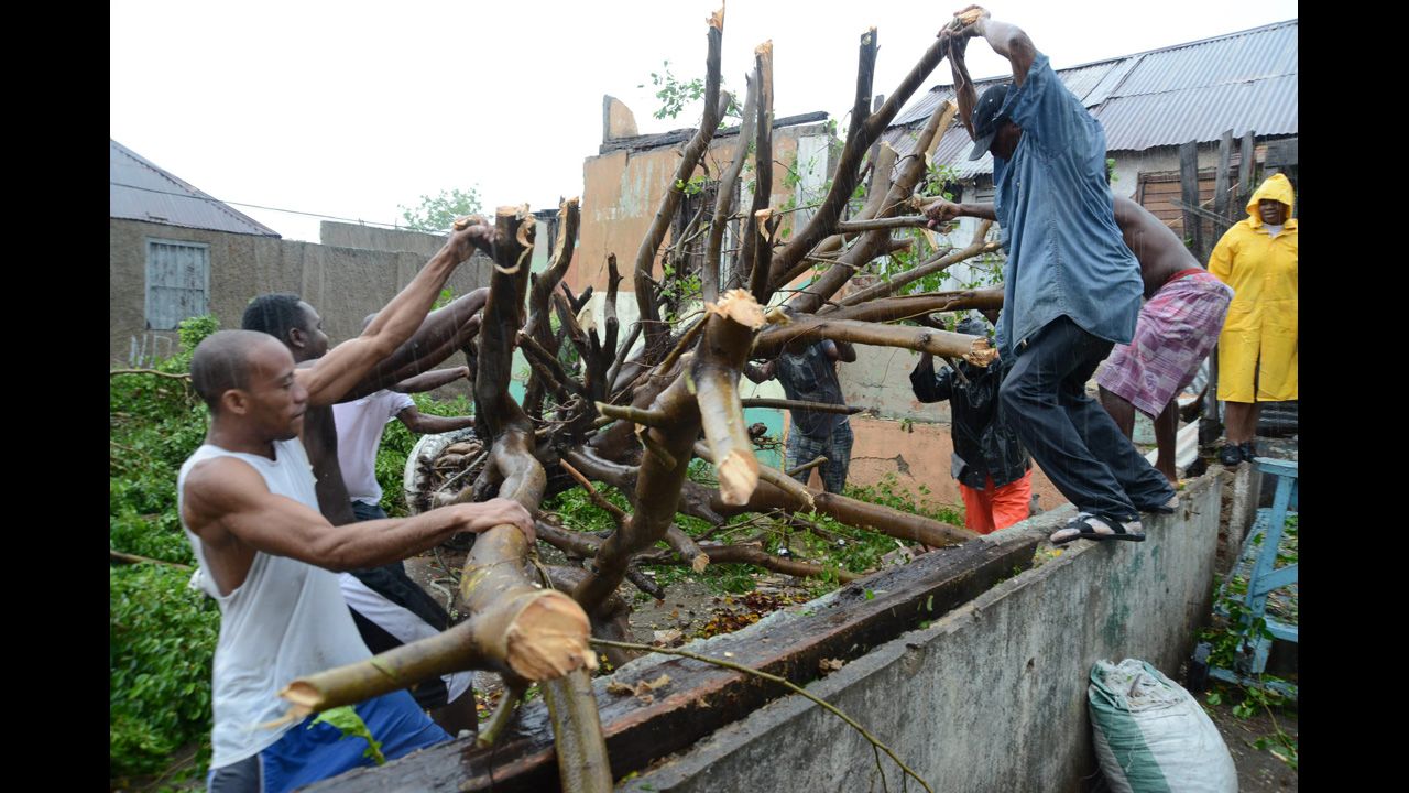 Men deal with downed tree branches after heavy rain caused by Hurricane Sandy in Kingston, Jamaica, on Wednesday, October 24.