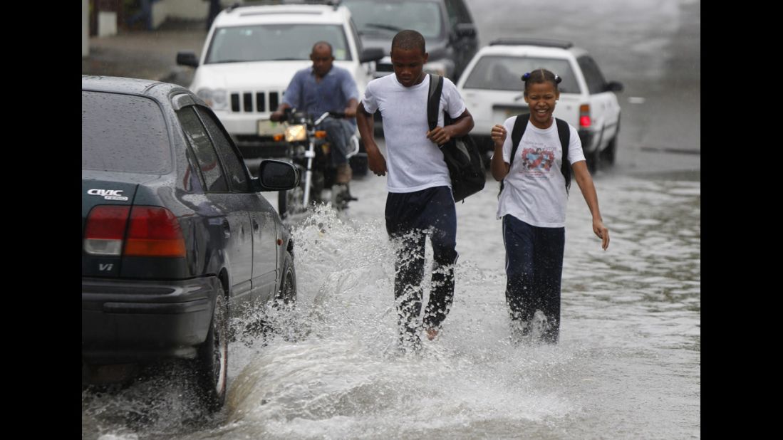 Students walk in floodwater from Hurricane Sandy's rain in Santo Domingo on Wednesday.