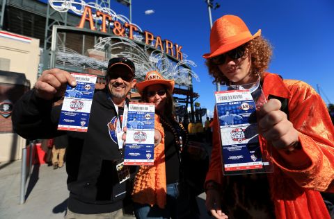 San Francisco Giants fans hold up their tickets to the game outside the stadium.