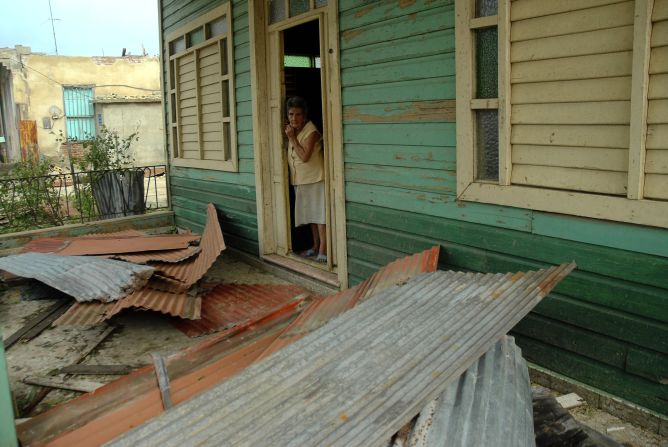 A woman peers out the door of her house Thursday after it was damaged by Hurricane Sandy in Bayamo, Cuba.