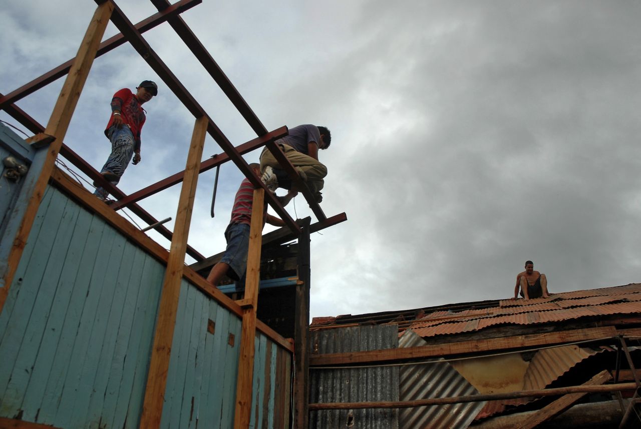 Residents in Bayamo, Cuba, try to fix a house damaged by hurricane Sandy on Thursday.