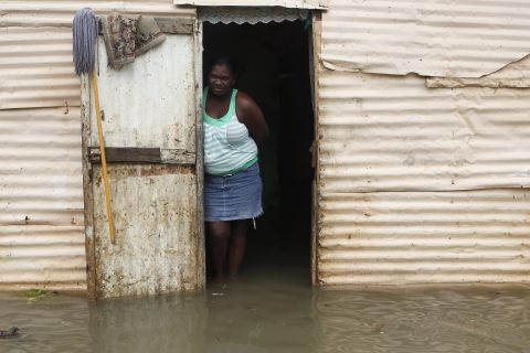 A woman stands at the entrance of her house surrounded by flood water after heavy rain in Santo Domingo on Thursday.