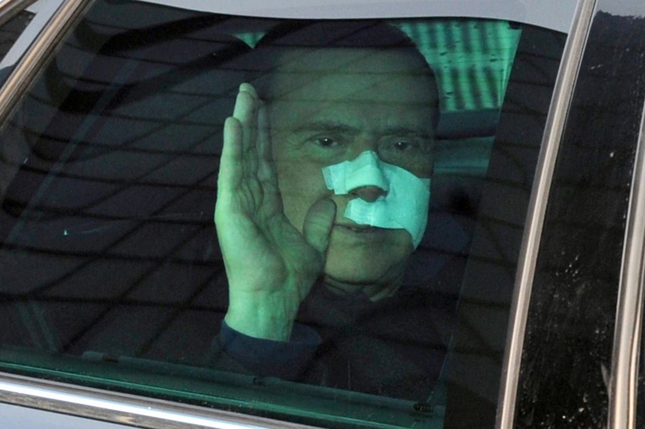 Berlusconi waves to journalists as he leaves a Milan hospital in December 2009 after suffering severe facial wounds in an attack at a rally.