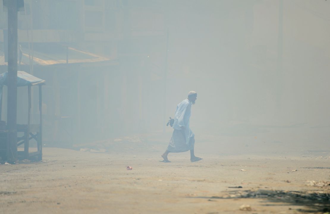 A Muslim walks amid burning houses in Sittwe, capital of Myanmar's western state of Rakhine, on June 12.