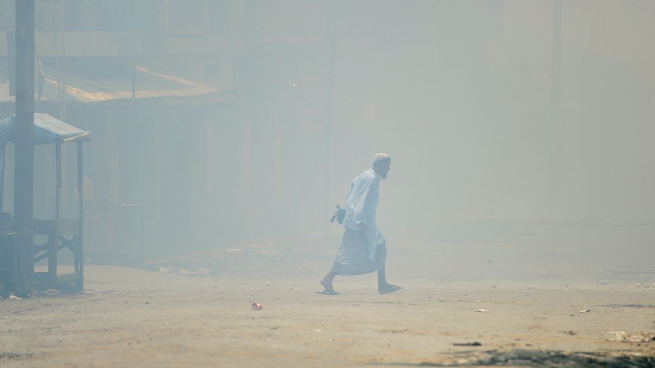 A Muslim walks amid burning houses in Sittwe, capital of Myanmar's western state of Rakhine, on June 12.