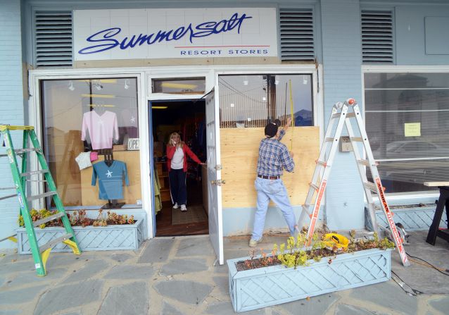 Bob Kaege takes a measurement while boarding up a shop in Cold Spring, New Jersey, on Saturday as Marie Jadick speaks on the telephone getting an updated weather report in preparation for Hurricane Sandy.