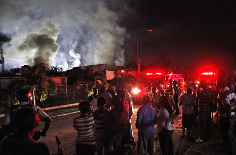 Residents watch firefighters battle a blaze in Kingston, Jamaica, on Friday. The fire, which destroyed the home, was started by a faulty generator that was triggered when Sandy caused a blackout, firefighters said.