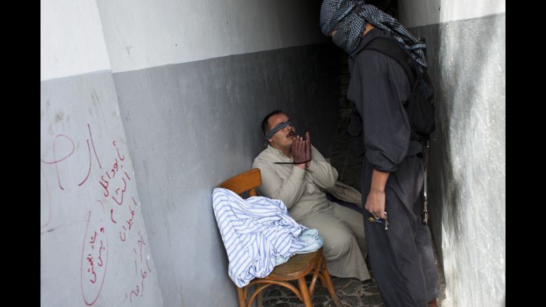 A Syrian rebel interrogates a handcuffed and blindfolded man suspected of being a pro-regime militiaman in Aleppo on October 26.