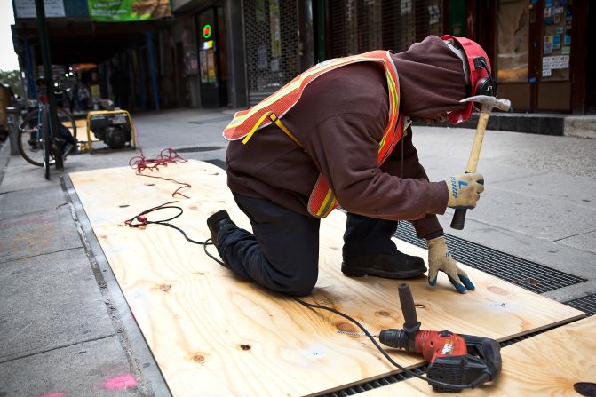 A construction worker covers air vents Sunday to try to prevent the New York subway system from flooding by Hurricane Sandy. New York Gov. Andrew Cuomo announced a shutdown and suspension of all subway, bus and commuter rail service in response to the storm. 