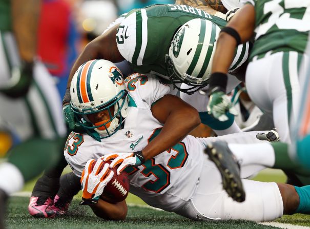 Daniel Thomas of the Dolphins scores a touchdown as David Harris of the Jets defends on Sunday.