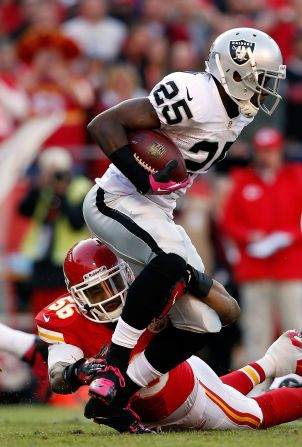 Running back No. 25 Mike Goodson of the Raiders carries the ball as inside No. 56 linebacker Derrick Johnson of the Chiefs defends.