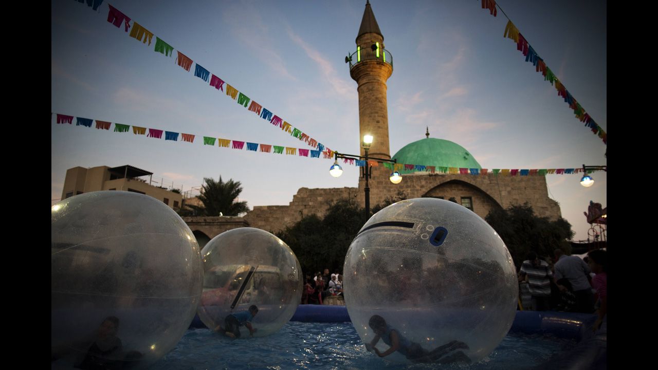 Arab Israeli children roll inside air balls floating on a pool at an amusement park on Saturday in the northern Israeli city of Acre.